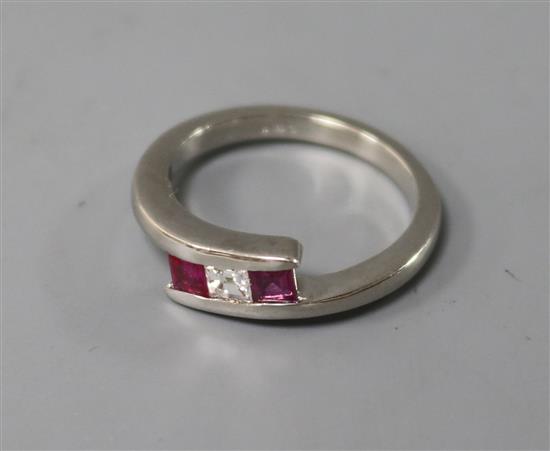 A modern 18ct white gold, three stone ruby and diamond ring, size N.